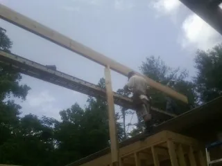 Carpenter setting a ridge beam over a new addition frame — Ice Dam Removal by Roofing Brothers in Shalimar