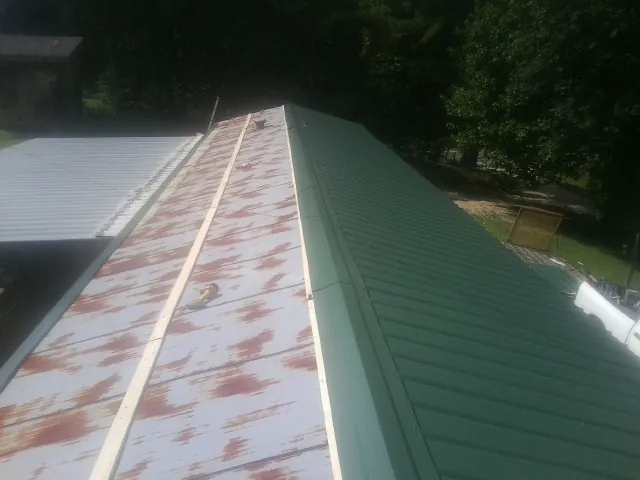 Old rusted panels beside newly installed green metal roofing — Wind Damage Roof Repair by Roofing Brothers in Shalimar