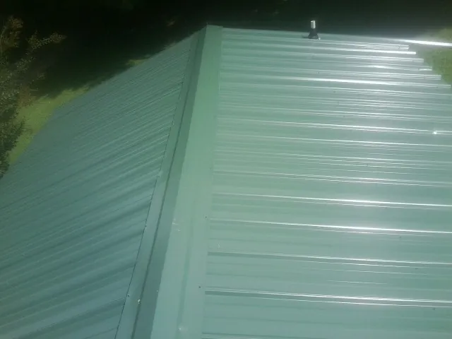 New green metal panels meeting at the ridge of a roof — Flat Roof Repair work by our crew in Shalimar