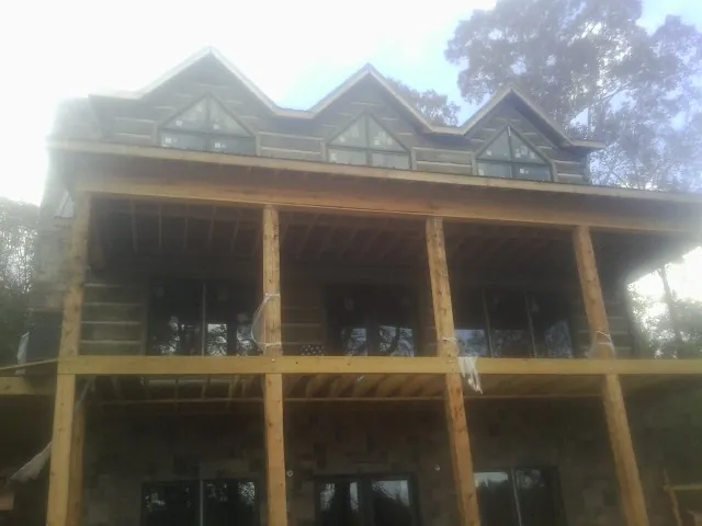 Dormers and porch framing on a large log home under construction — Roof Coating work by our crew in Shalimar