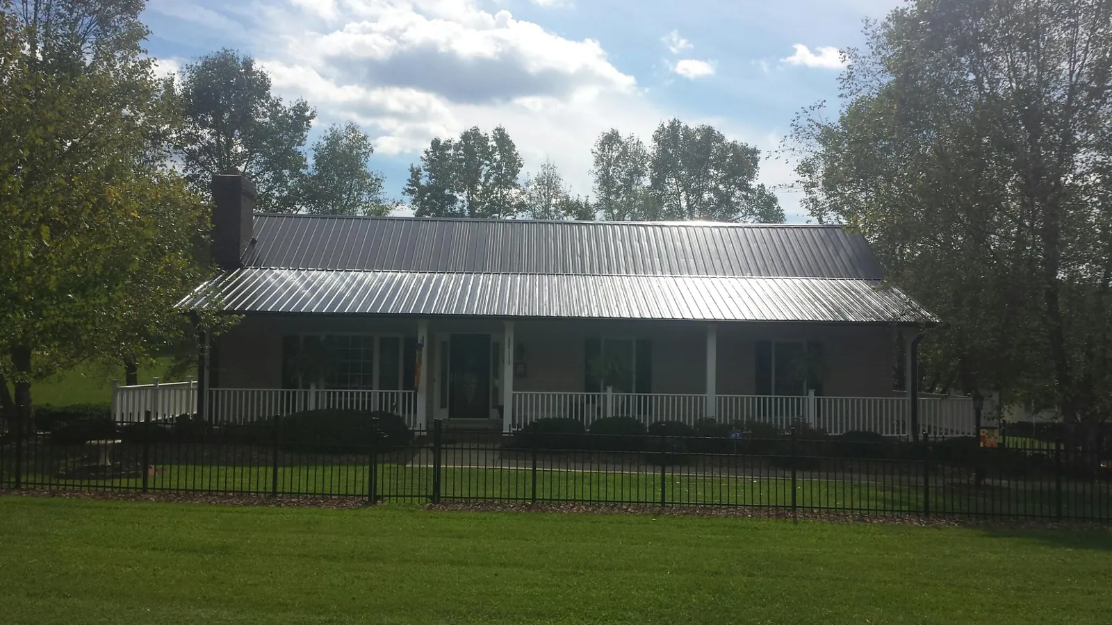 Gray metal roof on a brick ranch with a full width front porch — Gutter Guard Installation work by our crew in Shalimar