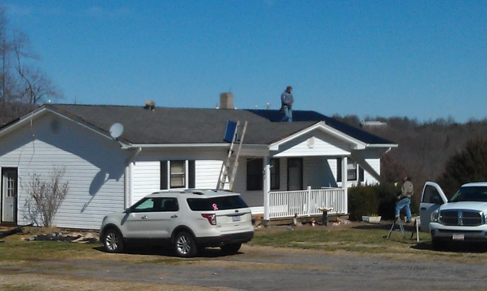 Roofers stripping shingles from a white ranch house roof in Shalimar
