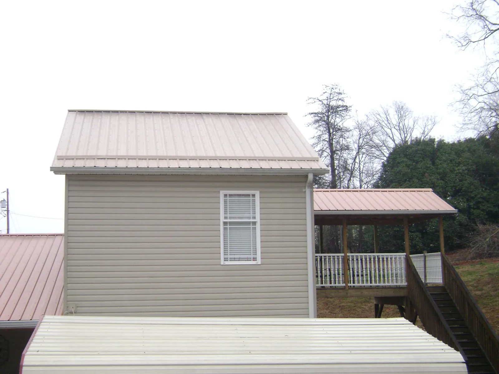 Tan metal roofs on a two story addition and attached porch, from a Roof Replacement job in Shalimar